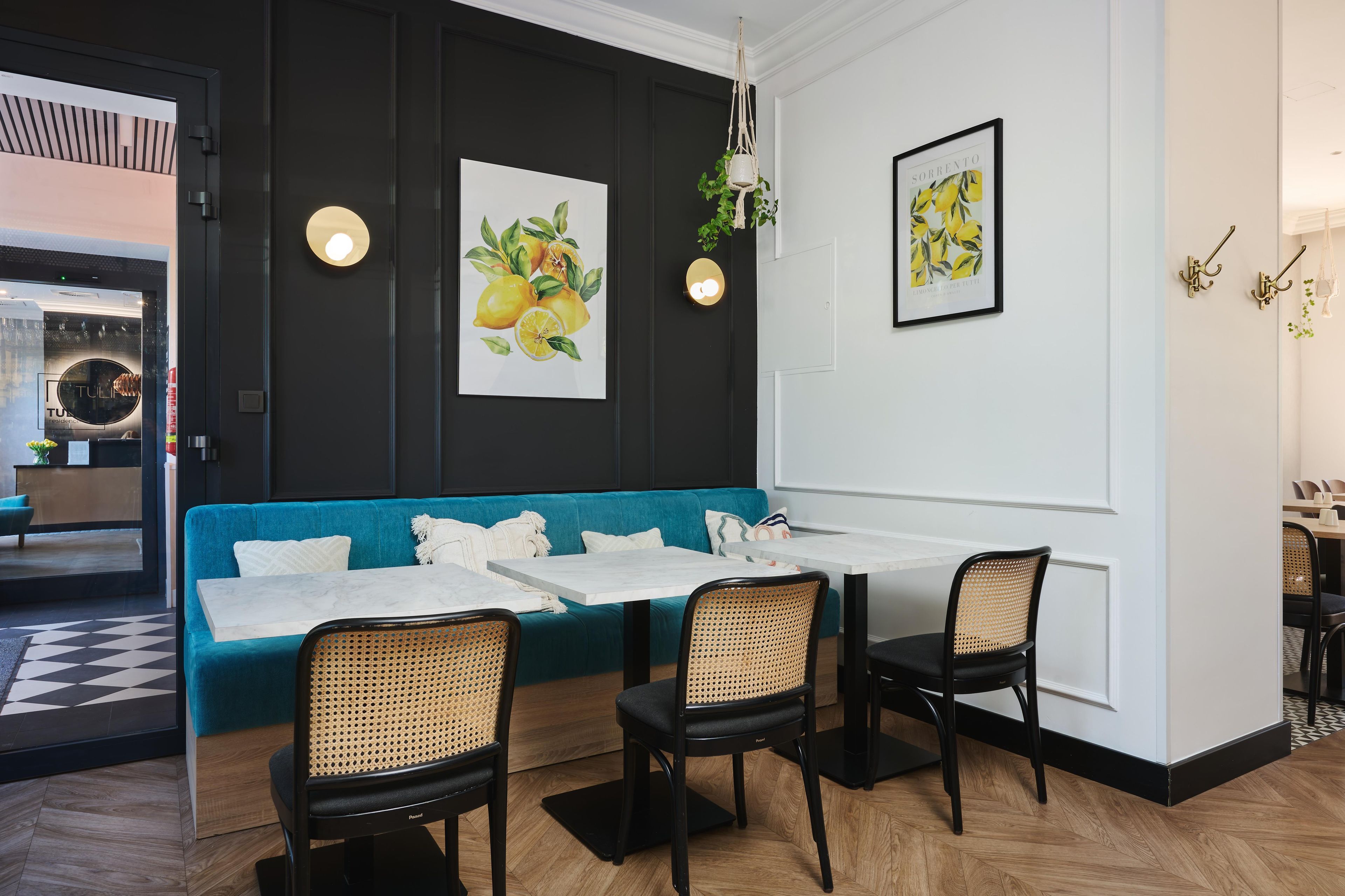 A modern interior with a teal sofa, black chairs, and a white table.