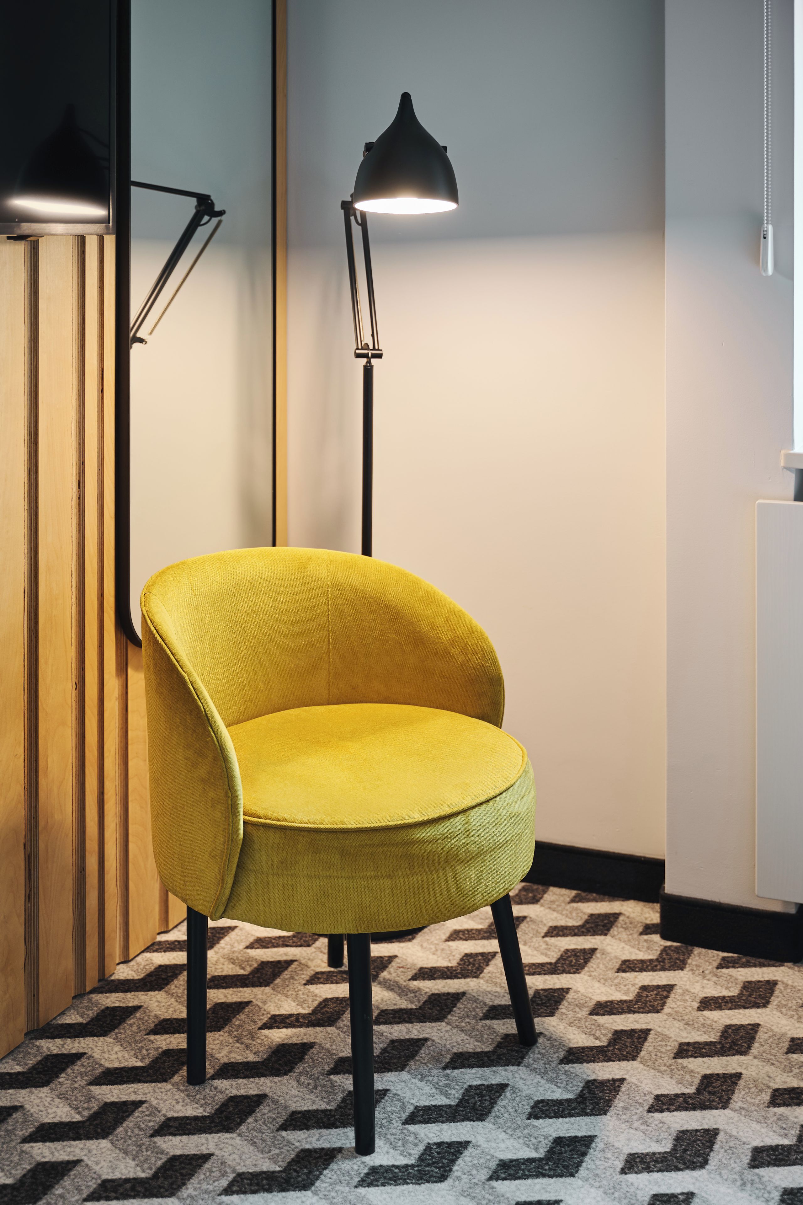 Un fauteuil jaune au dossier incurvé, placé sur un tapis à motifs.
