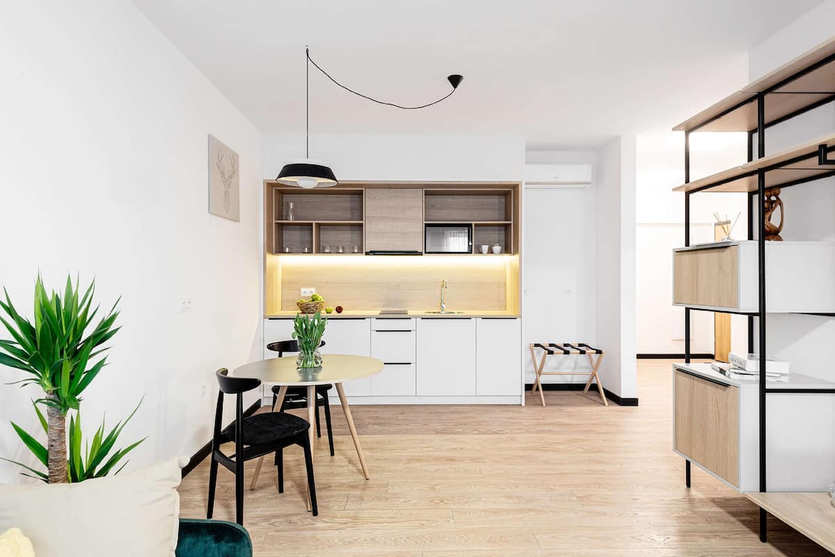A modern kitchen with white cabinets, a wooden countertop, and a hanging light fixture.