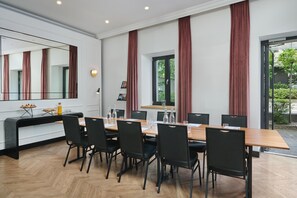 Un comedor moderno con una mesa larga, sillas negras y un espejo grande sobre ella.