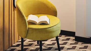 A yellow armchair with an open book, a floor lamp, and a patterned carpet.