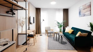 Een moderne woonkamer met een bank, salontafel, stoel, bureau met computer en een boekenkast.