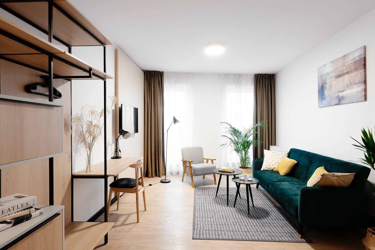 A modern living room with a sofa, a coffee table, a chair, a desk with a computer, and a bookshelf.