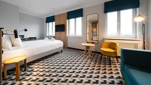 Een hotelkamer met een bed, een bureau, een stoel, een spiegel en een lamp.