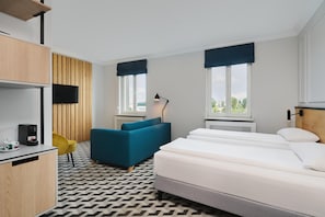 Une chambre d’hôtel comprenant un lit, un canapé, un bureau avec une machine à café et une télévision.
