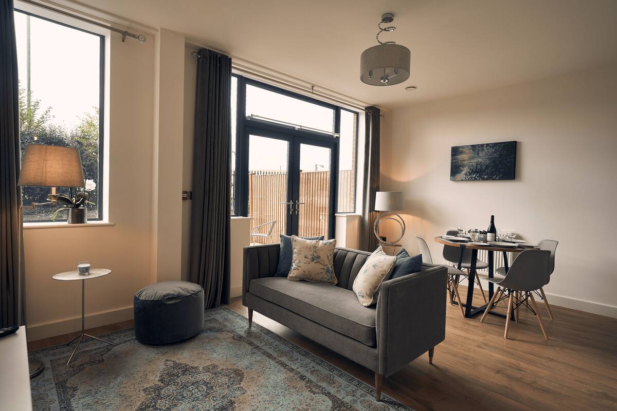A modern living room with a sofa, ottoman, and dining table.