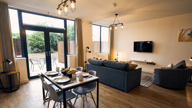 Una sala de estar moderna con comedor, un sofá y un televisor montado en la pared.
