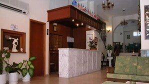 A reception area with a marble counter, potted plants, a green sofa, and a staircase.