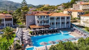 A hotel with a swimming pool, multiple balconies, and a view of the surrounding landscape.