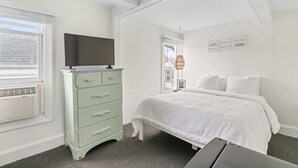 A bedroom with a bed, a dresser, a television, and a window with blinds. - The Melrose, 2B - Double Bed & Bath: Romantic Geta (Neptune Township)