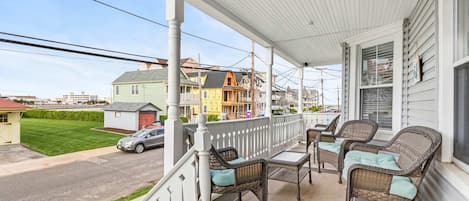 A covered porch with wicker furniture and a view of a street.