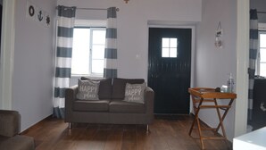 A living room with a sofa, a wooden table, and a black door.