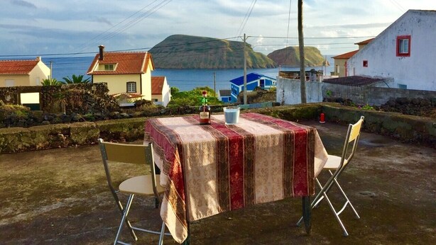 A table set outdoors with a tablecloth, a bottle, and a glass.