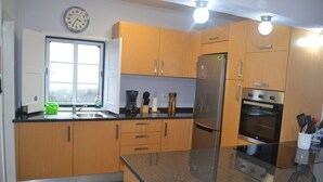 A modern kitchen with wooden cabinets, a stainless steel refrigerator, an oven, and a sink.
