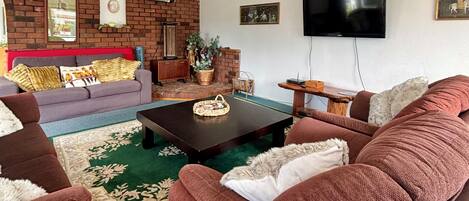 A living room with a brick wall, a television, and a sofa with cushions.