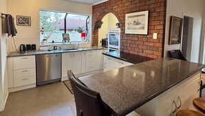 Een moderne keuken met een granieten aanrechtblad, roestvrijstalen apparatuur en een accentmuur van baksteen.