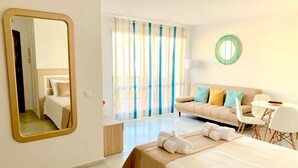 A hotel room with a bed, a sofa, a dining table, and a mirror. - Apartamento Studio Marina Suite (Benalmádena)