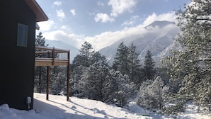 Een houten gebouw met een balkon dat uitkijkt over een besneeerd landschap en bergen.