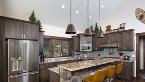 Een moderne keuken met een groot eiland, granieten aanrechtbladen en een accentmuur van steen.