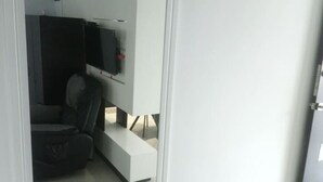 Ein modernes Zimmer mit Glastür zu einem Wohnbereich mit Sofa, Couchtisch und flachbildfernseher an der Wand.