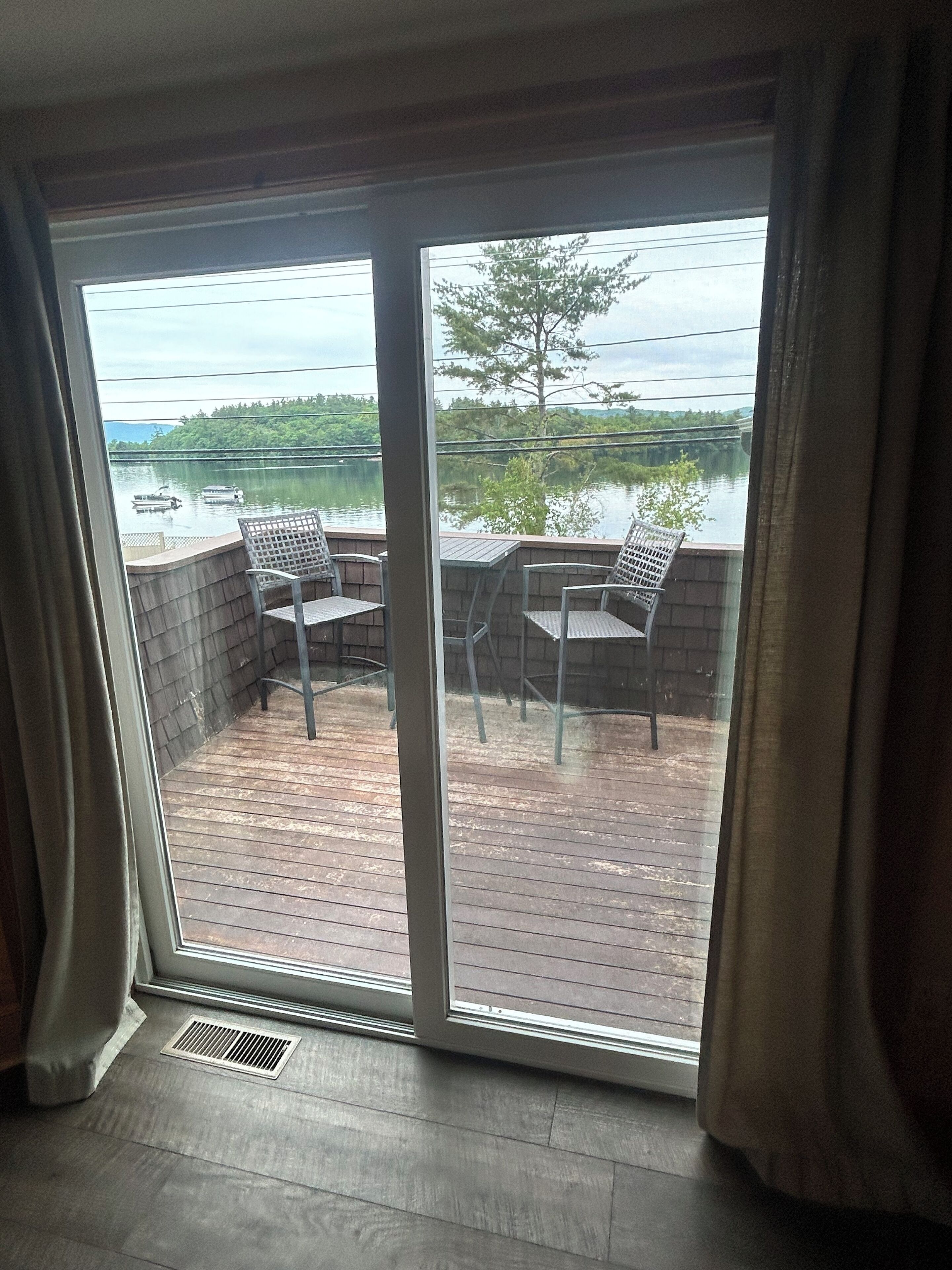Une pièce dotée d’une grande porte-fenêtre coulissante donnant sur une terrasse extérieure avec deux chaises et une table.