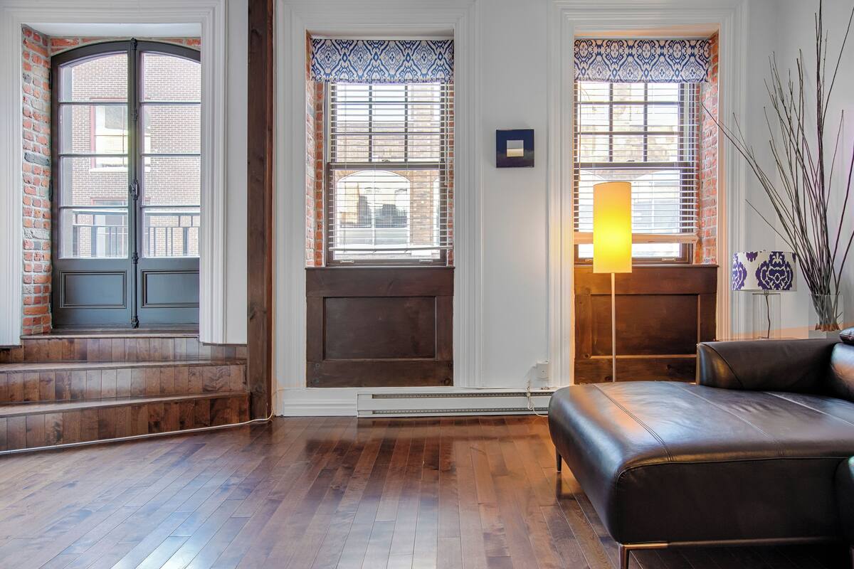 A room with a fireplace, a sofa, and a window with blinds.