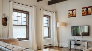 Een woonkamer met een bank, een televisie en een lamp.