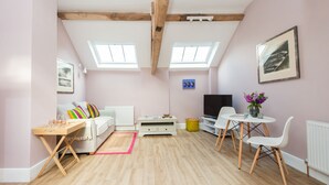 Un salon confortable avec un canapé, une table basse, un téléviseur et un coin repas avec des chaises.