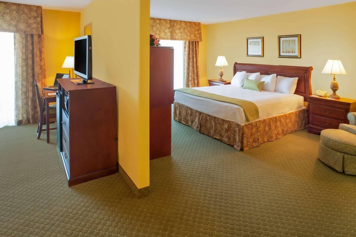 A hotel room with a bed, desk, television, and two bedside lamps.