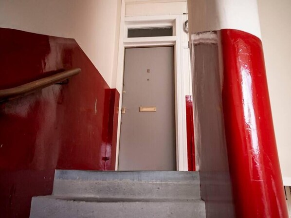 A staircase with red and white painted walls leading to a door.