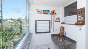 Une cuisine moderne dotée d’un plan de travail en granit, d’un évier en acier inoxydable et d’une fenêtre donnant sur un paysage urbain.