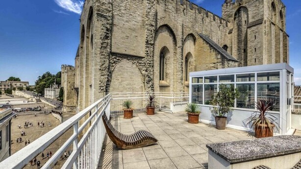 Un edificio histórico de piedra con ventanas arqueadas y un balcón con macetas.
