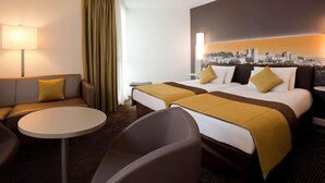 Una habitación de hotel con una cama, un sofá, una mesita y una silla.