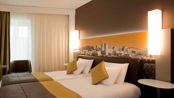 Habitación de hotel con dos camas, un mural de paisaje urbano en la pared y vistas de la ciudad a través de amplios ventanales.