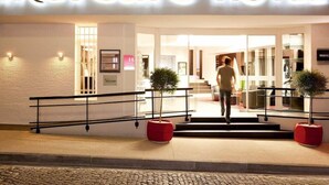 Exterior del Hotel Mercure con una fachada moderna, una escalera que conduce a la entrada y plantas en macetas en la base.