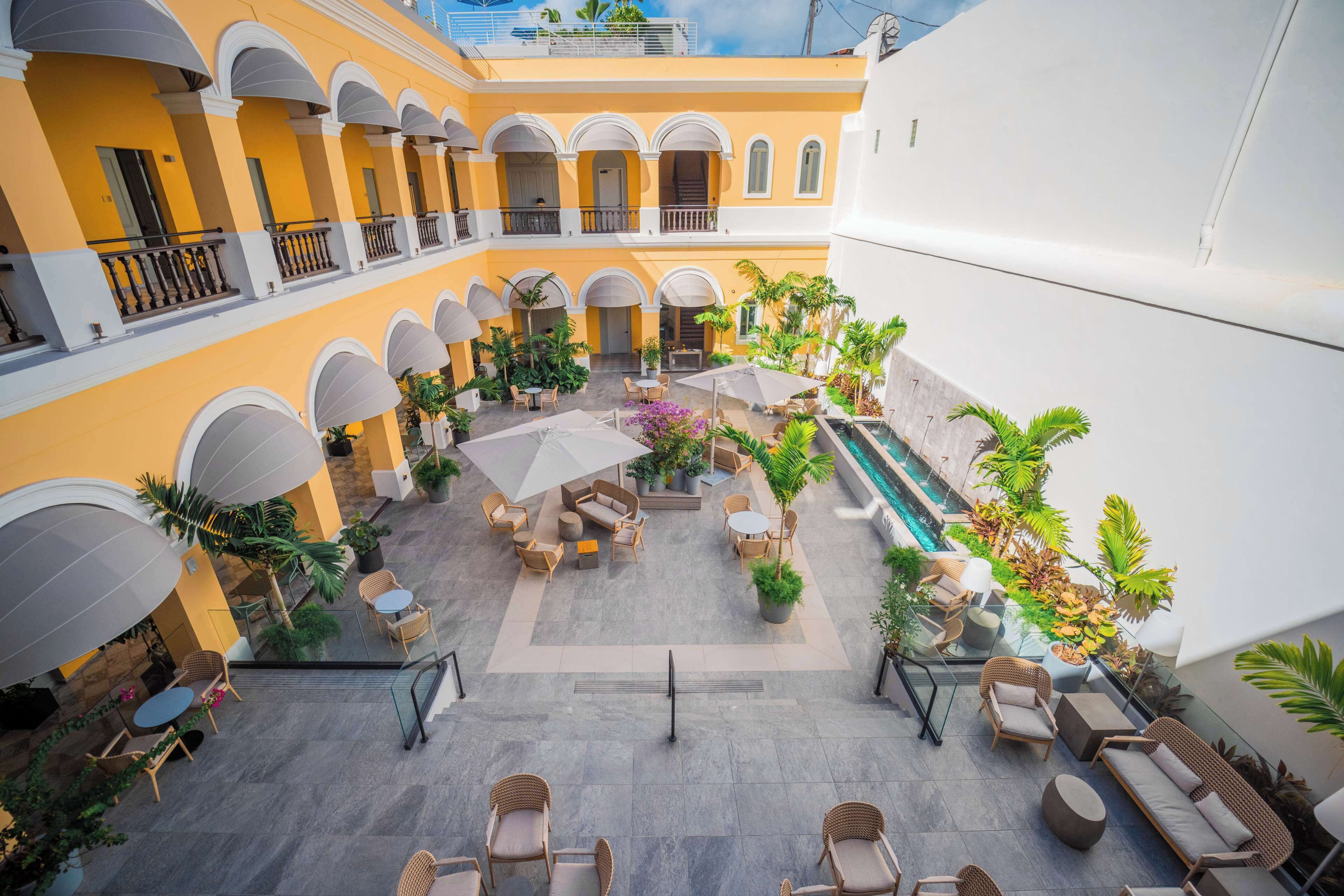 Une cour avec des espaces de détente en plein air, une piscine et une végétation luxuriante.