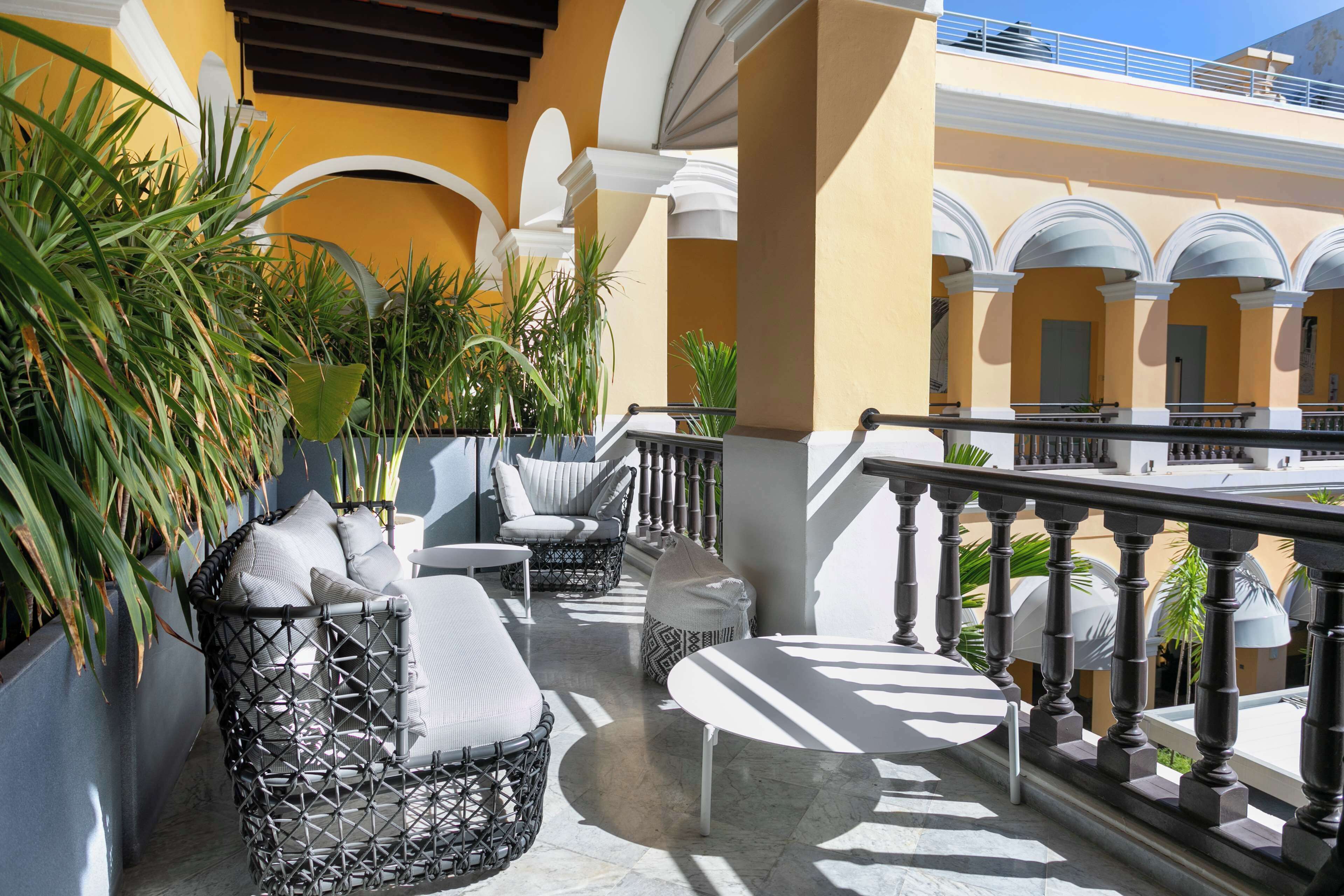 A balcony with wicker furniture, a round table, and potted plants.