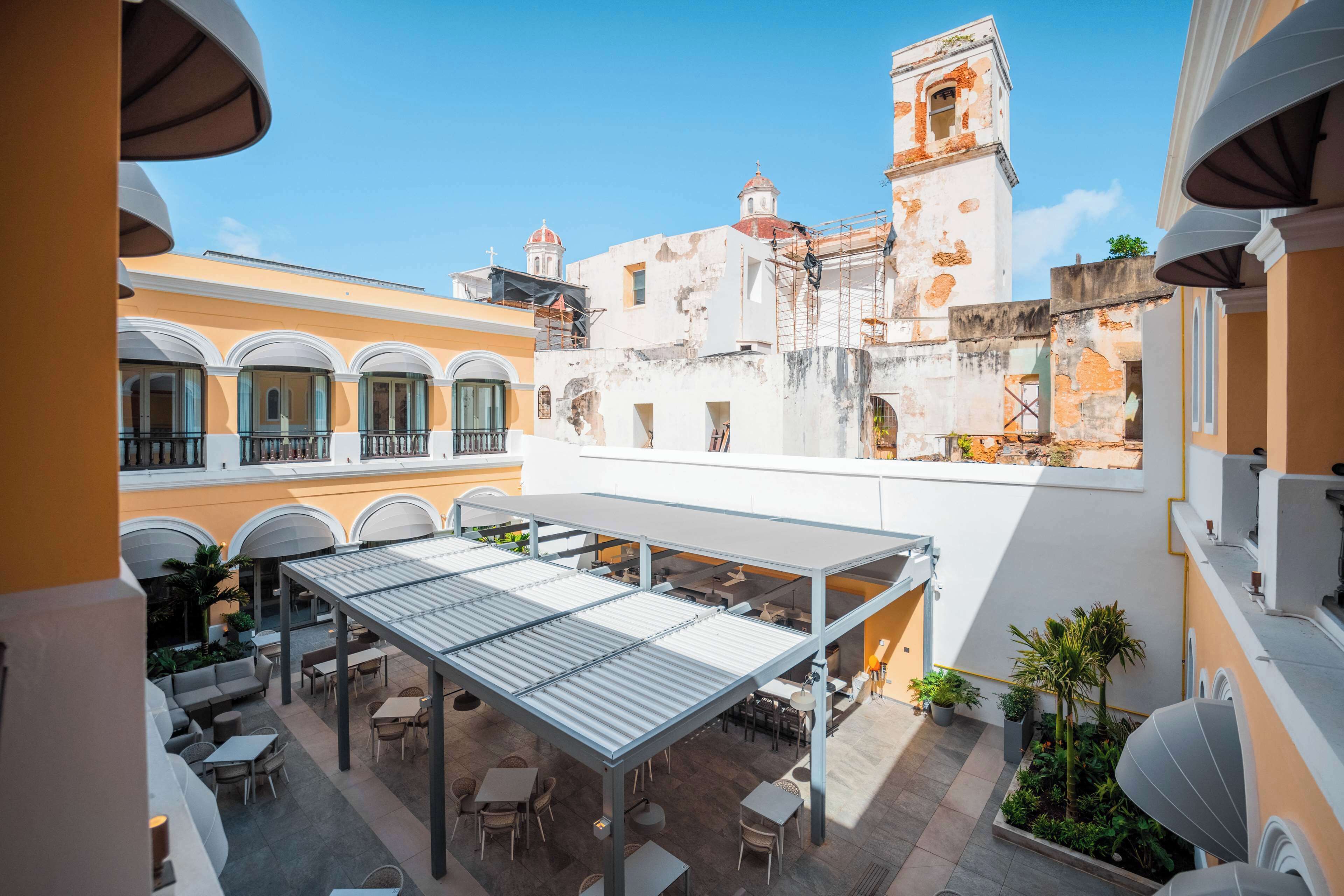 A courtyard with outdoor seating, a covered area, and a view of historic buildings in the background.