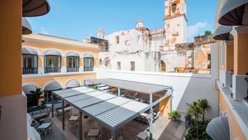 A courtyard with outdoor seating, a covered area, and a view of historic buildings in the background.