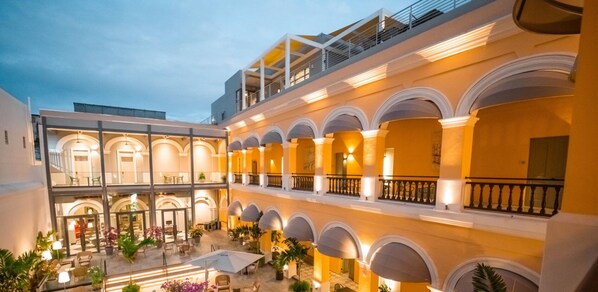 Experience the classic charm of our hotel's multi-level atrium, featuring a serene courtyard with outdoor seating and lush greenery.