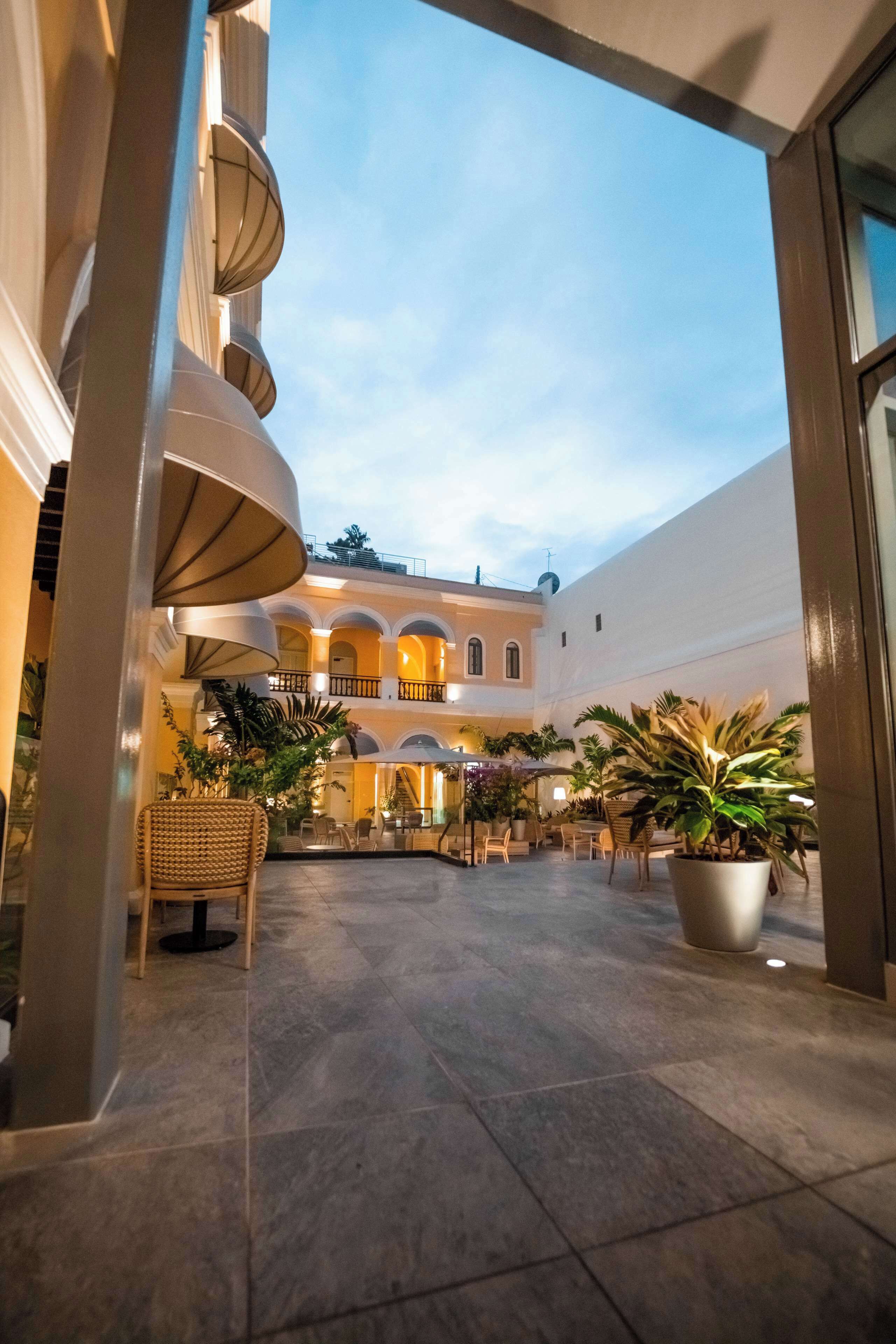 A courtyard with tiled flooring, potted plants, and outdoor seating.