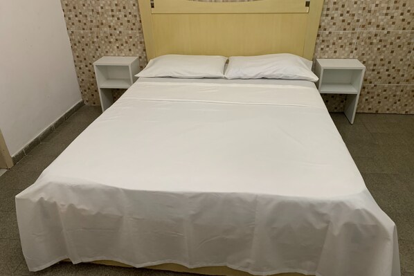A neatly made bed with a white bedspread, two bedside tables, and a headboard. - Mar Azul Hotel (Maceió)