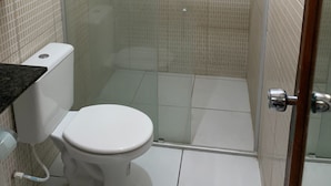 Un baño con inodoro, ducha y puerta de cristal.
