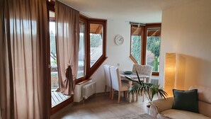 A cozy living room with a sofa, a coffee table, and a dining area with chairs and a table. - Ferienwohnung Bärenhofweg am Titisee (Titisee)