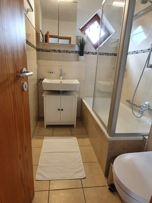 Ein Badezimmer mit Waschbecken, Spiegel, Schrank, Dusche und Toilette.