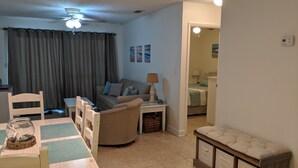 Un salon comprenant un canapé, une table à manger avec des chaises, une lampe et un ventilateur de plafond.