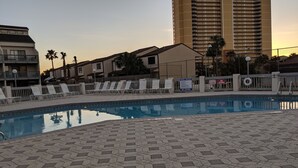 Une piscine équipée de chaises longues et entourée d’une clôture.