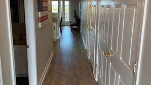 A hallway with wooden flooring, white doors, and a ceiling light fixture.