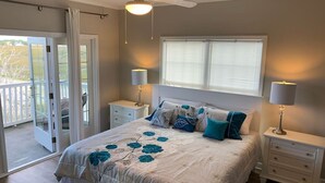 A bedroom with a bed, two bedside tables, a ceiling fan, and a window with blinds.
