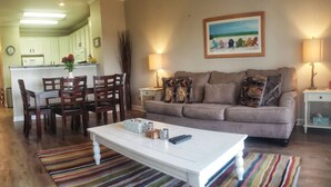 A living room with a white coffee table, striped rug, and a sofa with patterned cushions.